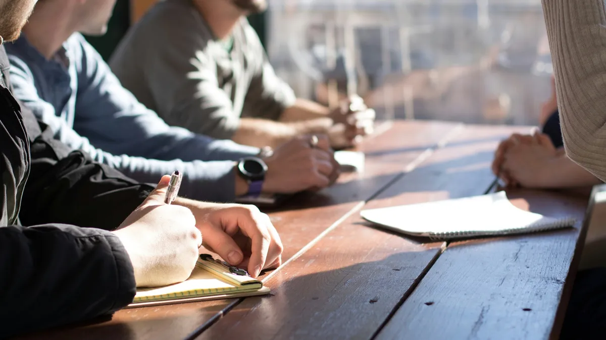 Executives taking notes around a wooden table during a strategy discussion.